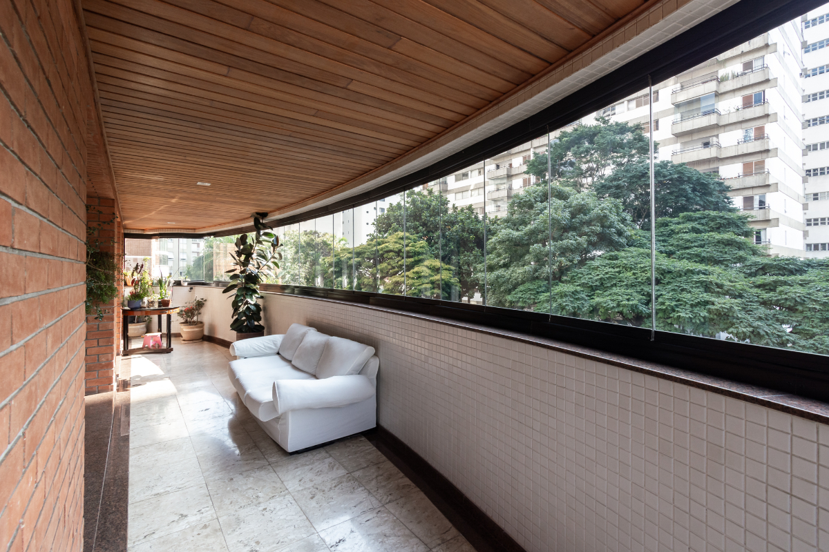 Varanda do apartamento com fechamento em vidro e plantas
